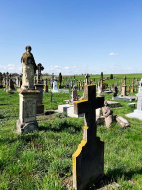 Khorostkiv, Ukrayna - 23 Nisan 2025: Gökyüzünün altında yeşil çimlerle çevrili eski bir mezarlık.