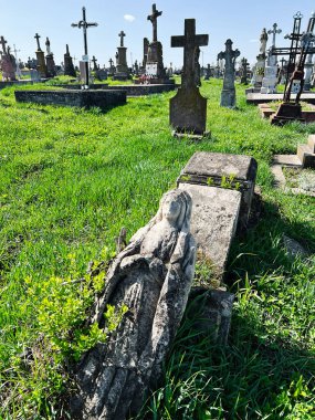 Khorostkiv, Ukrayna - 23 Nisan 2025: Huzurlu mezarlık manzarası mezar taşları ve canlı yeşil çimenler arasında eğilmiş heykel