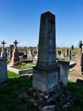 Khorostkiv, Ukrayna - 23 Nisan 2025: Parlak gökyüzü altında yeşilliklerle çevrili yıpranmış mezar taşlarının yer aldığı güzel bir mezarlık.