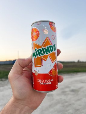 Kyiv, Ukrayna - 23 Nisan 2025: Mirinda 'nın sıfır şekerli portakallı gazozunu dışarıda manzaralı arka planda tutan kişi.