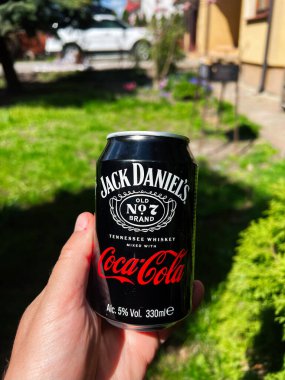 Kyiv, Ukrayna - 23 Nisan 2025: Jack Daniel 'in Coca-Cola kutusunu güneşli bir arka planda tutan kişi
