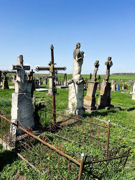 Khorostkiv, Ukrayna - 23 Nisan 2025: Kırsal bir mezarlığın ortasındaki demir çitle çevrili yıpranmış mezar işaretleri.