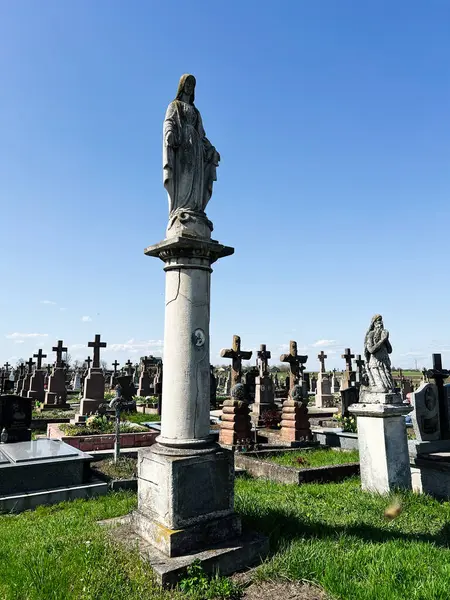 Khorostkiv, Ukrayna - 23 Nisan 2025: Canlı mavi gökyüzü altında heykel ve haçlarla dolu bir mezarlık.