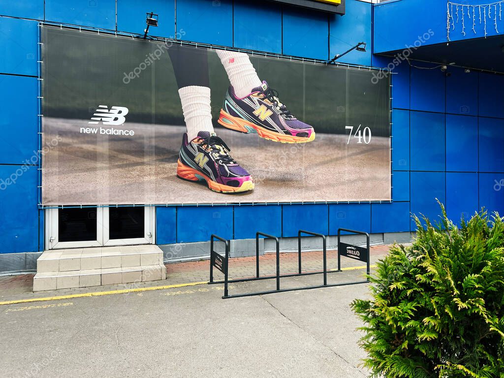 Khmelnytsky, Ukraine - April 23, 2025: Outdoor advertisement featuring stylish New Balance 740  sneakers on a blue building near a sidewalk.