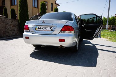 Kyiv, Ukrayna - 28 Nisan 2025: Gümüş Mitsubishi Lancer Sedan güneşli bir şehir merkezinde açık kapılı park yeri