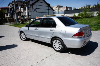 Kyiv, Ukrayna - 28 Nisan 2025: Asfalt zemine park etmiş gümüş renkli Mitsubishi Lancer marka bir sedan