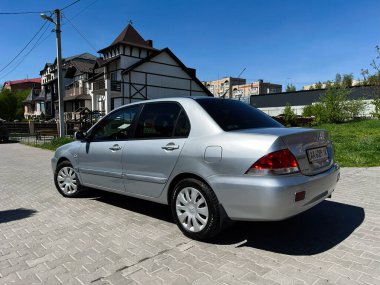 Kyiv, Ukrayna - 28 Nisan 2025: Gümüş Mitsubishi Lancer Sedan arabası kaldırımlı bir sokağa park edildi.