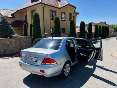 Kyiv, Ukrayna - 28 Nisan 2025: Mitsubishi Lancer açık bir evin yanına park etmiş, kapıları açık..