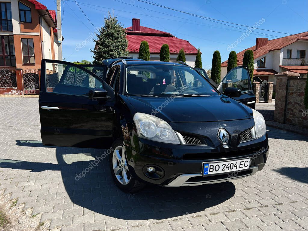 Kyiv, Ukraine - April 28, 2025: Black Renault Koleos SUV with open doors showcased on an urban cobblestone street