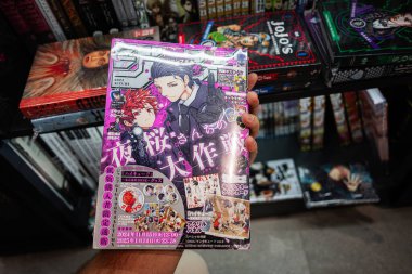 Ivano-Frankivsk, Ukrayna - 29 Nisan 2025: Diğer renkli kitaplarla çevrili bir kitapçıda bir manga dergisini tutmak