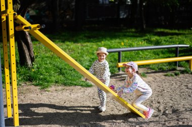 Çocuklar neşeli ve neşeli bir oyun bahçesinde tahterevalliden zevk alıyorlar.