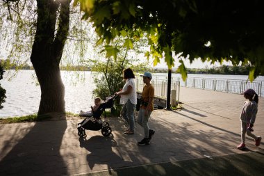 Ağaçlarla ve güneş ışığıyla çevrili bir nehirde gezinen bir aile..