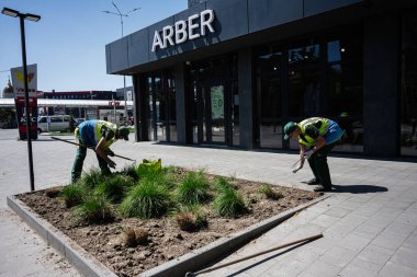 Ivano-Frankivsk, Ukrayna - 29 Nisan 2025: Ticari bir bina girişinin yakınındaki bir şehir ortamında fabrikalarını koruyan iki işçi