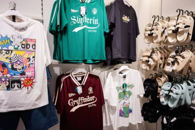 Ivano-Frankivsk, Ukrayna - 29 Nisan 2025: Perakende alışveriş müşterileri için çeşitli renkli grafik tişörtleri ve günlük ayakkabılar sergileniyor