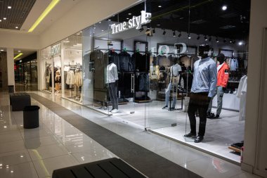 Ivano-Frankivsk, Ukrayna - 29 Nisan 2025: Modeller ve modern cam cephe tasarımının yer aldığı moda Gerçek Stil giyim mağazası.