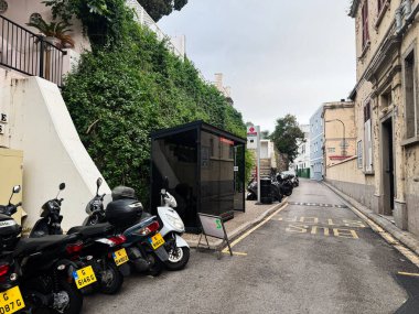 Cebelitarık, İngiltere - 01 Mayıs 2025: Park etmiş motosikletler, otobüs durağı tabelası ve sessiz atmosfer içeren antika Cebelitarık sokağı.