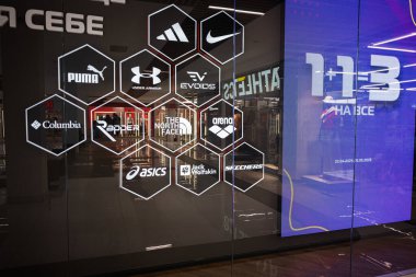 Ivano-Frankivsk, Ukrayna - 29 Nisan 2025: Cam mağaza vitrininde çeşitli ünlü giyim ve spor giyim markalarının logoları sergileniyor.