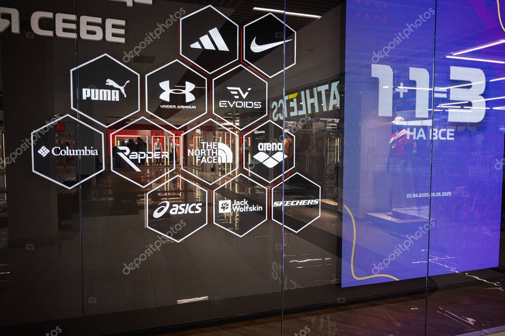 Ivano-Frankivsk, Ukraine - April 29, 2025: Glass storefront showcasing logos of various renowned clothing and sportswear brands.