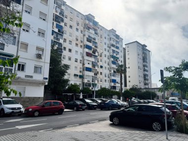Malaga, İspanya - 02 Mayıs 2025: Malaga, İspanya 'da bulutlu bir gökyüzünün altında park edilmiş arabaları olan yüksek konut binaları