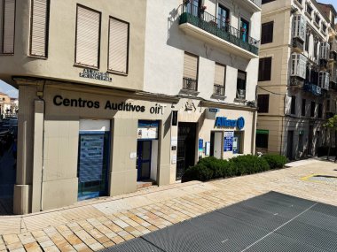 Malaga, İspanya - 02 Mayıs 2025: Centros Auditivos oirT ve İspanya 'nın Malaga kentindeki güneşli bir sokakta dairelerin yer aldığı şehir sahnesi