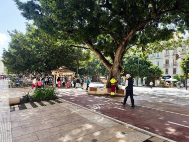 Malaga, İspanya - 02 Mayıs 2025: Malaga 'da yayalar, yeşillikler ve hareketli faaliyetlerin sergilendiği hareketli sokak manzarası