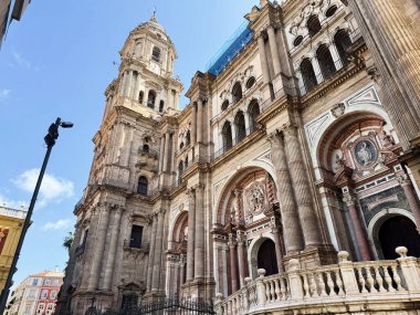 Malaga, İspanya - 02 Mayıs 2025: Malaga 'nın tarihi katedralinin heybetli mavi gökyüzüne karşı karmaşık taş cephesi