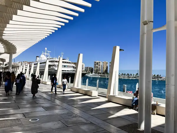Malaga, İspanya - 02 Mayıs 2025: Güneşli gökyüzü ve gezinen insanlarla Malaga 'daki şık yürüyüş yolu ve manzaralı liman Palmeral de las Sorpresas.
