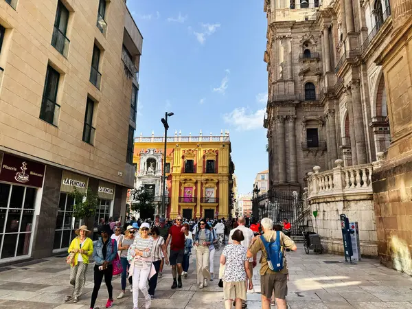 Malaga, İspanya - 02 Mayıs 2025: Turistler güneşli bir günde Malaga 'da güzel tarihi yapıların yakınında hareketli bir caddeyi keşfediyorlar