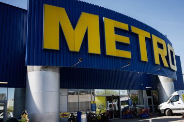 Ivano-Frankivsk, Ukrayna - 29 Nisan 2025: Metro toptan binasının girişi açık mavi arka plan ve koyu sarı tabela