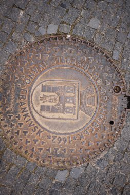 Ivano-Frankivsk, Ukrayna - 29 Nisan 2025: İvano-Frankivsk şehrinin kaldırım taşı zemininde metin ve dekoratif tasarımların yer aldığı rögar kapağı.