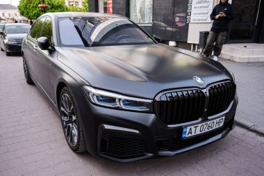 Ivano-Frankivsk, Ukrayna - 29 Nisan 2025: Şehir kaldırımına park edilmiş yüksek kaliteli siyah BMW M7 G70 arabası