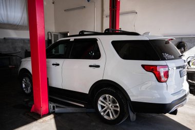 Kyiv, Ukrayna - 02 Mayıs 2025: Hidrolik kaldırma sistemindeki bir otomotiv tamir atölyesine yerleştirilmiş beyaz bir Ford Explorer SUV