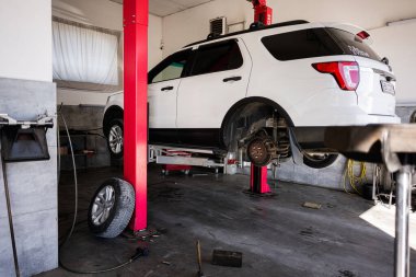 Kyiv, Ukrayna - 02 Mayıs 2025: Beyaz Ford Explorer SUV servis sırasında temiz bir oto tamirhanesinde hidrolik asansörle kaldırıldı