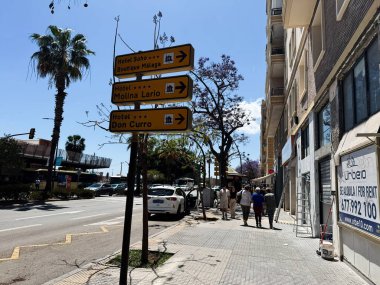 Malaga, İspanya - 02 Mayıs 2025: Malaga 'da güneş ışığı altında yerel otellere yönelik yön işaretleri bulunan şehir caddesi