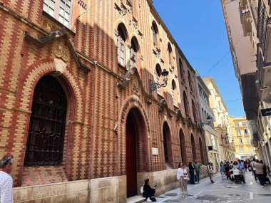 Malaga, İspanya - 02 Mayıs 2025: Kırmızı tuğlalı Sacred Heart Okulu binası Gotik unsurların yoğun Malaga caddesi boyunca yer aldığı.