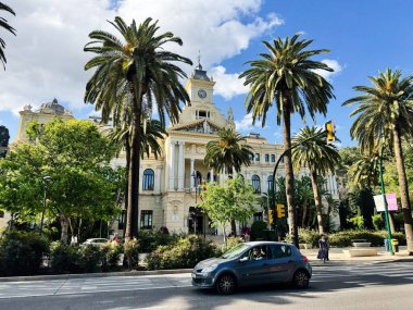 Malaga, İspanya - 02 Mayıs 2025: İspanya 'nın Malaga kentinde güneşli bir günde palmiye ağaçları ile tarihi belediye binası mimarisi