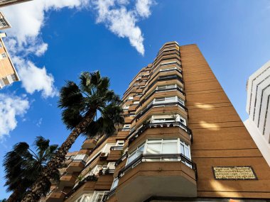 Malaga, İspanya - 02 Mayıs 2025: Malaga, İspanya 'da palmiye ağaçları altında yemyeşil kentsel mimari