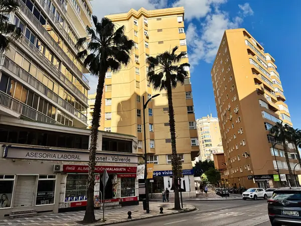 Malaga, İspanya - 02 Mayıs 2025: Sarı binalar, palmiye ağaçları ve bulutlu gökyüzü ile Malaga kentsel mimarisi