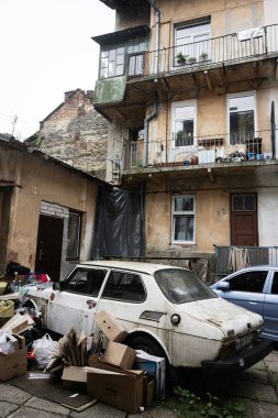Lviv, Ukrayna - 04 Mayıs 2025: Çürük ve dağınık binalarla çevrili eski bir arabanın bulunduğu avlu sahnesi.