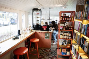 Lviv, Ukrayna - 04 Mayıs 2025: Kitaplıklar, tezgah ve gevşetilmiş ambiyansla aydınlanan modern kafe.