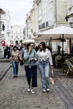 Lviv, Ukrayna - 04 Mayıs 2025: İnsanlar Lviv, Ukrayna 'da binalar ve açık kafelerle çevrili pitoresk bir sokakta geziniyorlar. 