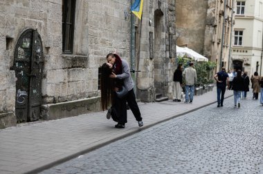 Lviv, Ukrayna - 04 Mayıs 2025: Lviv, Ukrayna 'da yaşayan insanlarla çevrili eski bir şehir sokağında tutkuyla kucaklaşan sevgi dolu bir çift. 