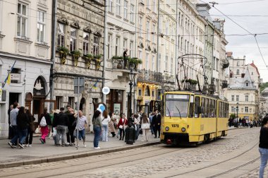 Lviv, Ukrayna - 04 Mayıs 2025: Lviv, Ukrayna 'da sarı bir tramvay ve tarihi binaların yer aldığı pitoresk bir şehir caddesi. 