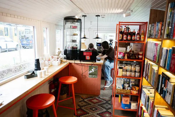 Lviv, Ukrayna - 04 Mayıs 2025: Kitaplıklar, tezgah ve gevşetilmiş ambiyansla aydınlanan modern kafe.