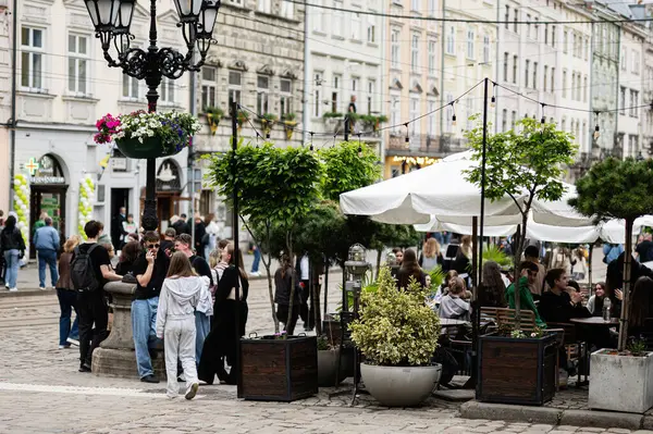 Lviv, Ukrayna - 4 Mayıs 2025: İnsanlar Ukrayna 'nın Lviv kentindeki büyüleyici tarihi bir sokakta sosyalleşiyor ve dışarıda yemek yiyor.. 