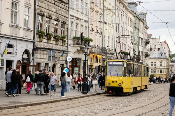 Lviv, Ukrayna - 04 Mayıs 2025: Lviv, Ukrayna 'da sarı bir tramvay ve tarihi binaların yer aldığı pitoresk bir şehir caddesi. 