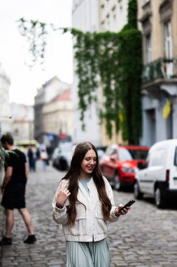 Lviv, Ukrayna - 04 Mayıs 2025: Bir kızın açık havada yürürken telefon tuttuğu yaşam tarzı
