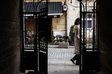 Lviv, Ukrayna - 04 Mayıs 2025: Bir kişi, Ukrayna 'nın başkenti Lviv' deki bir açık şehir avlusuna süs kapılarından geçerek binadan çıkıyor. 