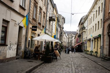 Lviv, Ukrayna - 04 Mayıs 2025: Lviv, Ukrayna 'da hareketli tarihi bir bölgede büyüleyici bir kaldırım taşı caddesi kafeler ve renkli mimari sergileniyor. 