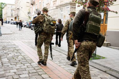 Lviv, Ukrayna - 4 Mayıs 2025: Ukrayna 'nın Lviv kentindeki tarihi bir çevrede yürüyen kamuflaj üniformalı silahlı kişiler. 